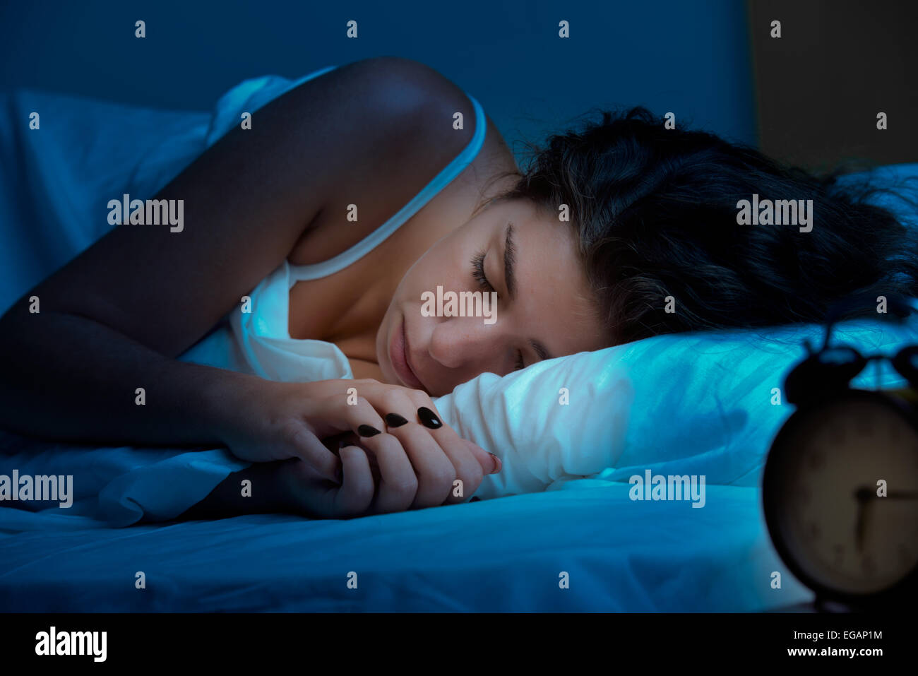 Woman sleeping in a bed in a dark bedroom Stock Photo
