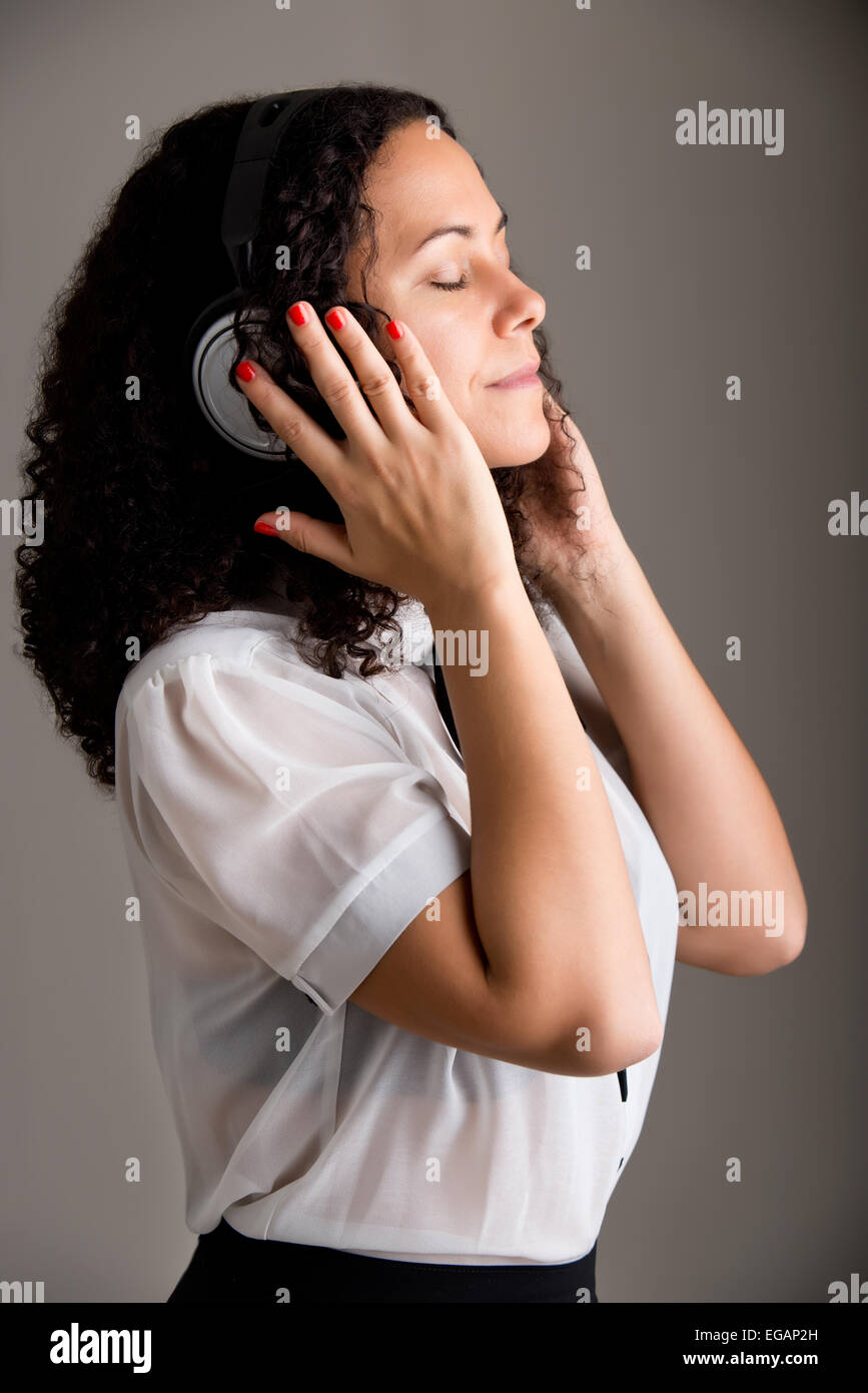 Young woman listening to music through her headphones, isolated in a dark background Stock Photo