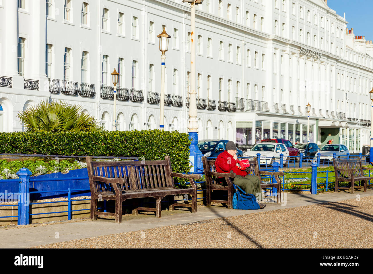 A Man Sits On A Bench Eating Fish and Chips, Eastbourne, Sussex, England Stock Photo