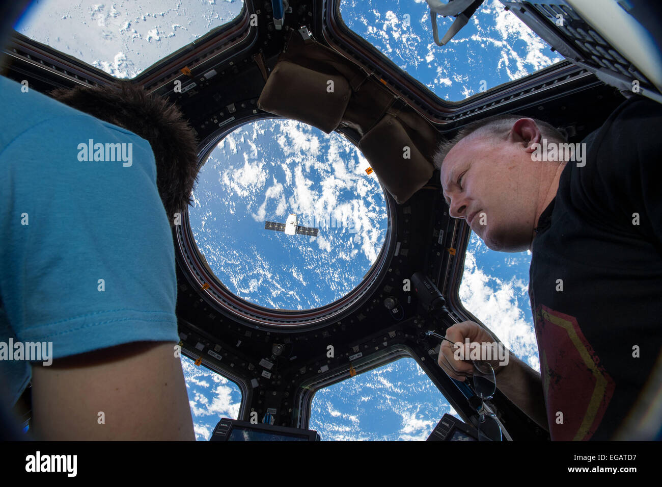 International Space Station Expedition 42 Commander and NASA Astronaut Barry Wilmore and European Space Agency Astronaut Samantha Cristoforetti view the SpaceX Dragon commercial cargo craft from inside the coupla as they maneuver the Canadarm 2 to dock the supply ship to the orbiting space station January 12, 2015 in Earth Orbit. Stock Photo