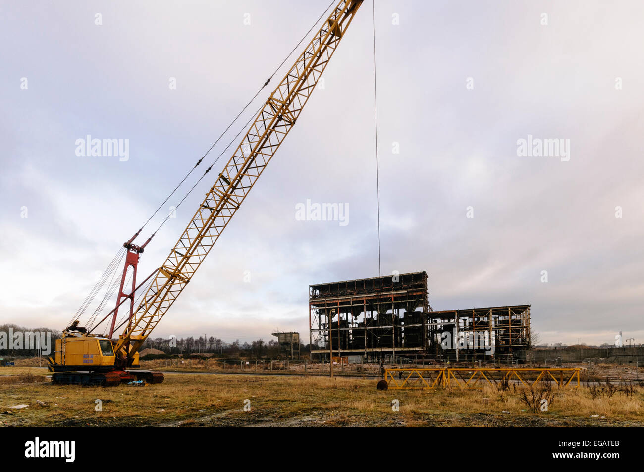 Crane with wrecking ball outside a semi-demolished power station Stock Photo