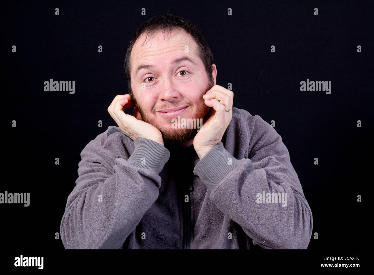 Portrait of man with hands under the chin looking into the camera, isolated on black Stock Photo
