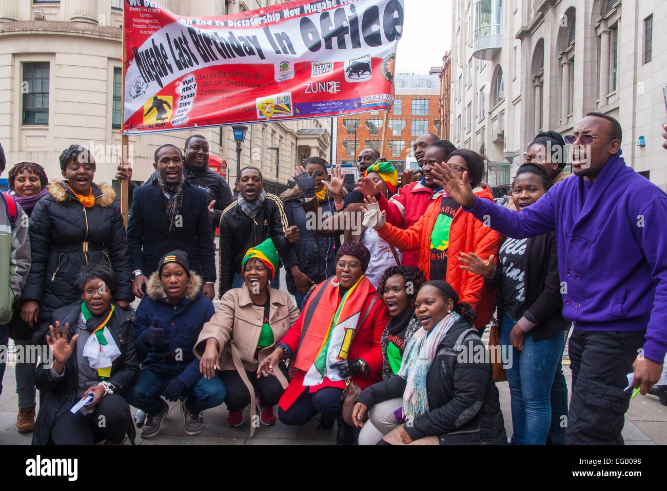 London, UK. 21st February, 2015. Dozens of exiled Zimbabweans gather outside their embassy in London proclaiming Mugabe's last birthday in office. Singing and dancing as they have done every Saturday since 2002, the group spoke with passersby and added yet more names to their petition. PICTURED: Zimbabwe Vigil protesters pose with a banner proclaiming this birthday - his 91st - is Mugabe's last in office. Credit:  Paul Davey/Alamy Live News Stock Photo