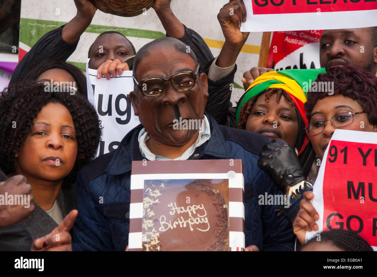 London, UK. 21st February, 2015. Dozens of exiled Zimbabweans gather outside their embassy in London proclaiming Mugabe's last birthday in office. Singing and dancing as they have done every Saturday since 2002, the group spoke with passersby and added yet more names to their petition. PICTURED: 'Mugabe' displays his birthday cake as back in Zimbabwe hundreds of guests prepare to dine on two elephants that have allegedly been butchered for his birthday celebrations at Victoria Falls. Credit:  Paul Davey/Alamy Live News Stock Photo