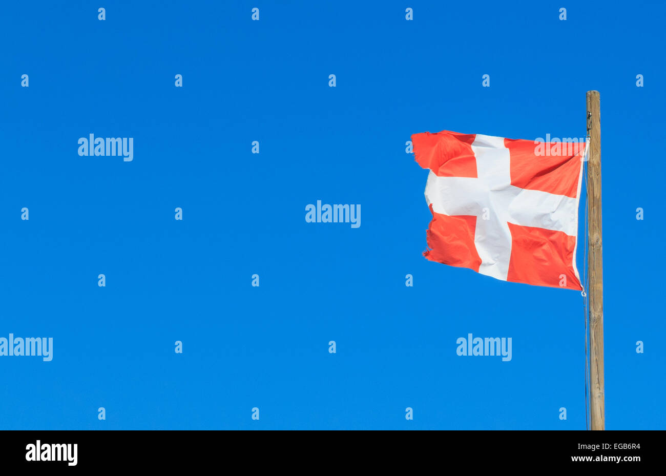 The read and white flag of the  Hauite Savoie (department 74) in France flying from a flagpole against a clear blue sky. Stock Photo