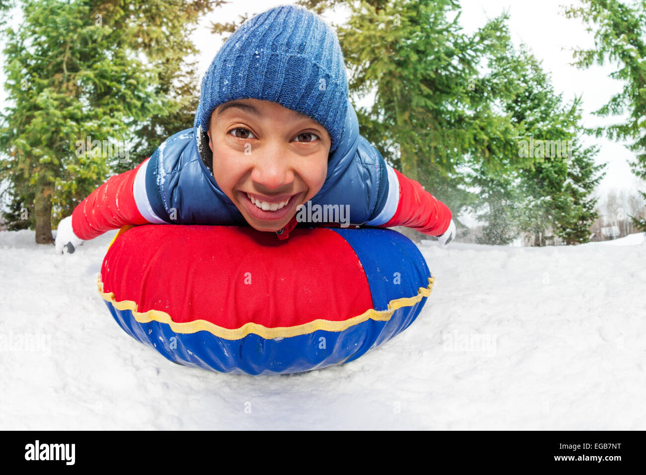 Close-up of excited boy on snow tube in winter Stock Photo