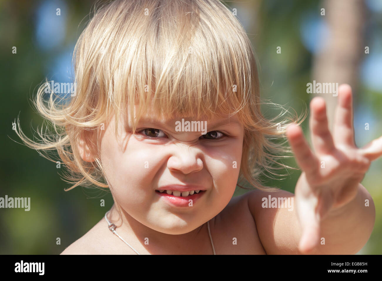 Outdoor closeup portrait of cute angry Caucasian blond baby girl Stock Photo