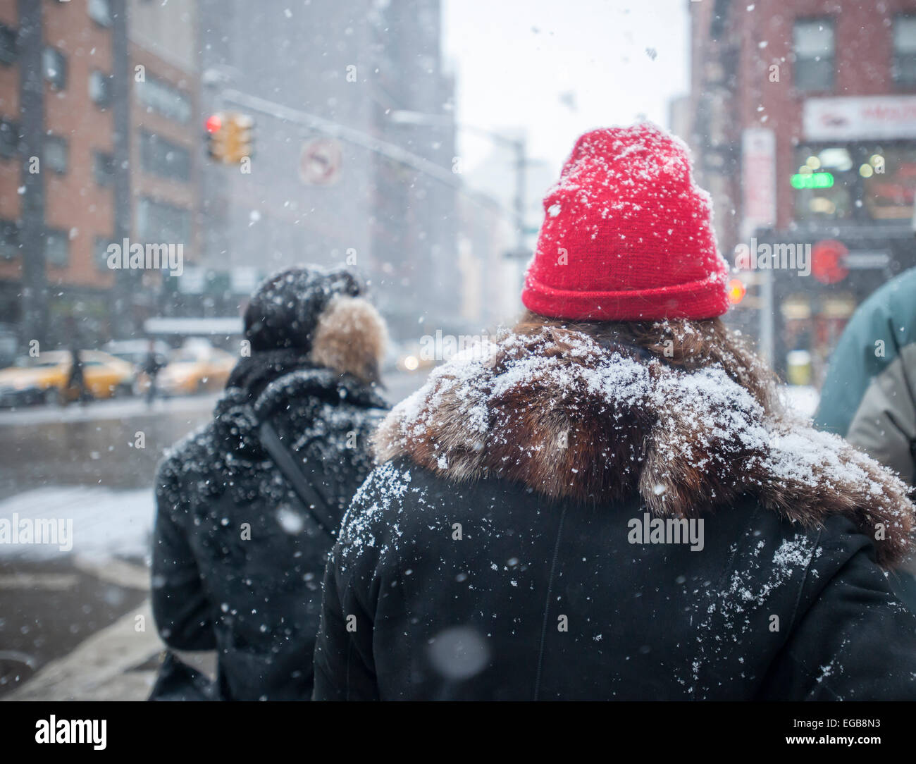 Snow covered pedestrians wait to cross Sixth Avenue in Chelsea in New York on Saturday, February 21, 2015.  A fast-moving winter storm arrives in New York depositing up to four inches of snow, covering the already existing mounds of dirty ice. (© Richard B. Levine) Stock Photo