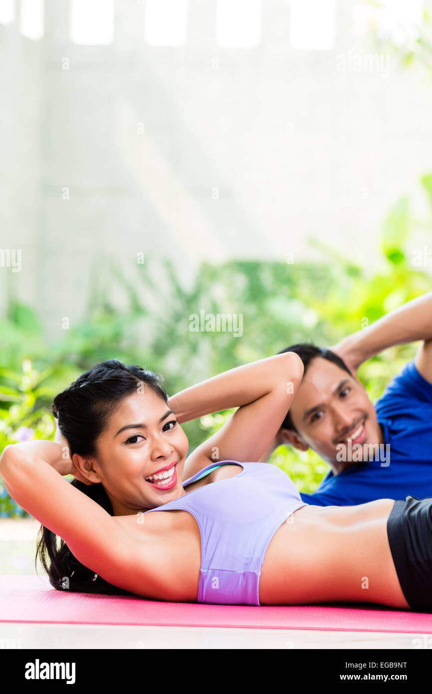 Asian fitness couple, man and woman, doing sit-up in tropical home Stock Photo