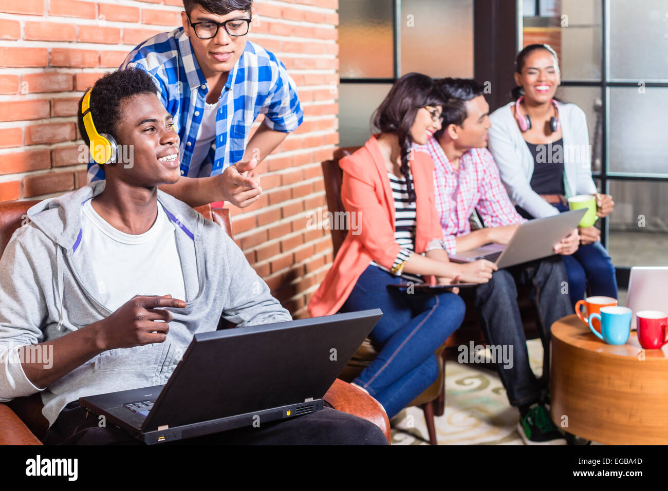 Computer programmer in start-up company coding, co-worker is looking ...