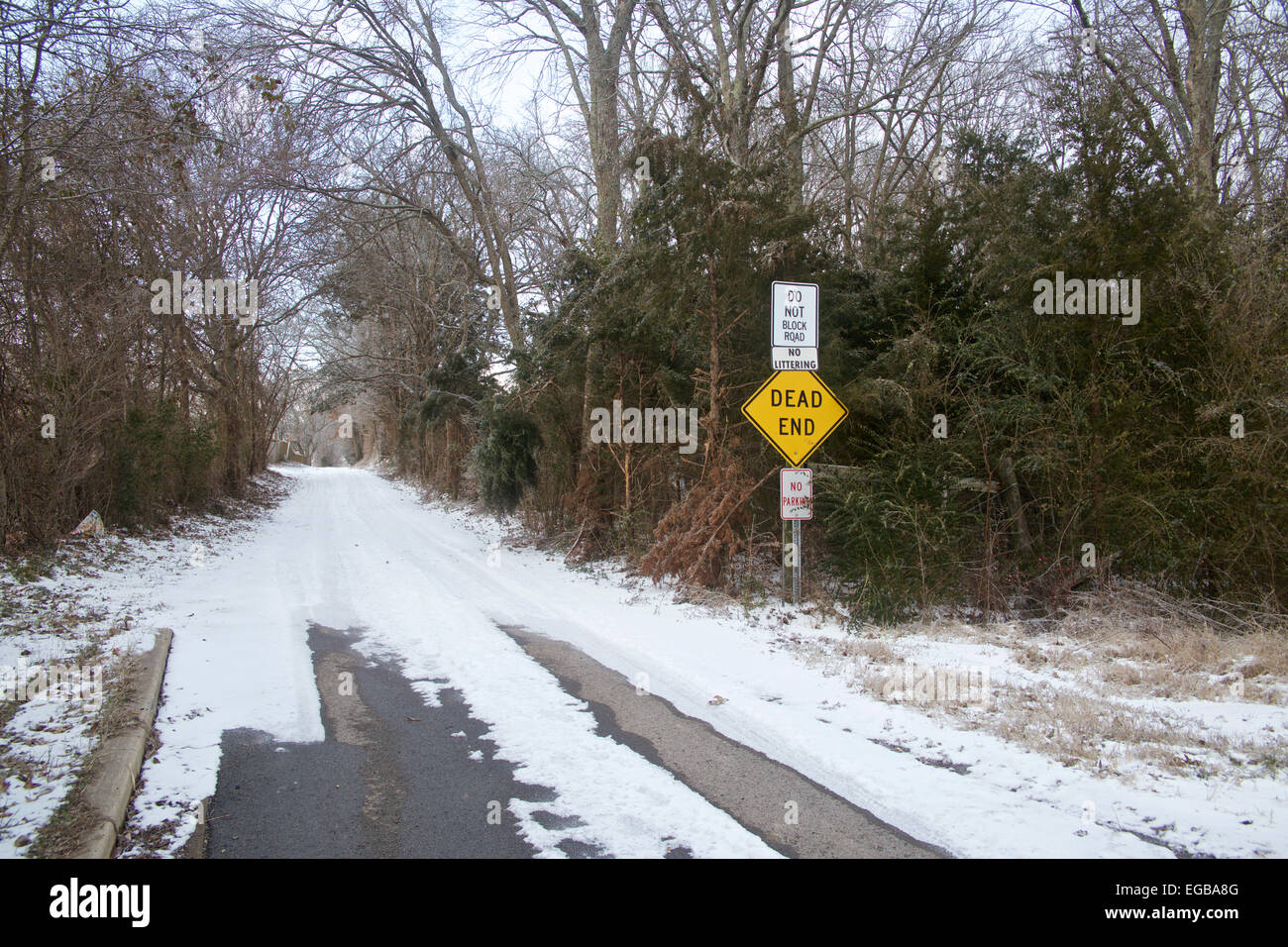 Snowy wooded roadway with dead end sign in front on entrance. Stock Photo