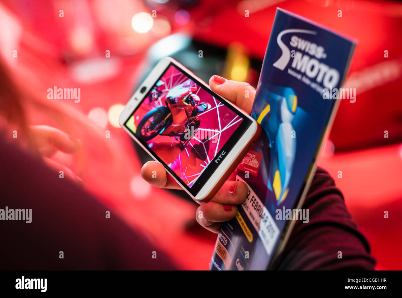 Zurich, Switzerland. 20th Feb, 2015. Red dream: a woman at the 'Swiss-Moto' motorcycle show in Zurich has just taken a smartphone picture of a Ducati Panigale supersport bike. Credit:  thamerpic/Alamy Live News Stock Photo