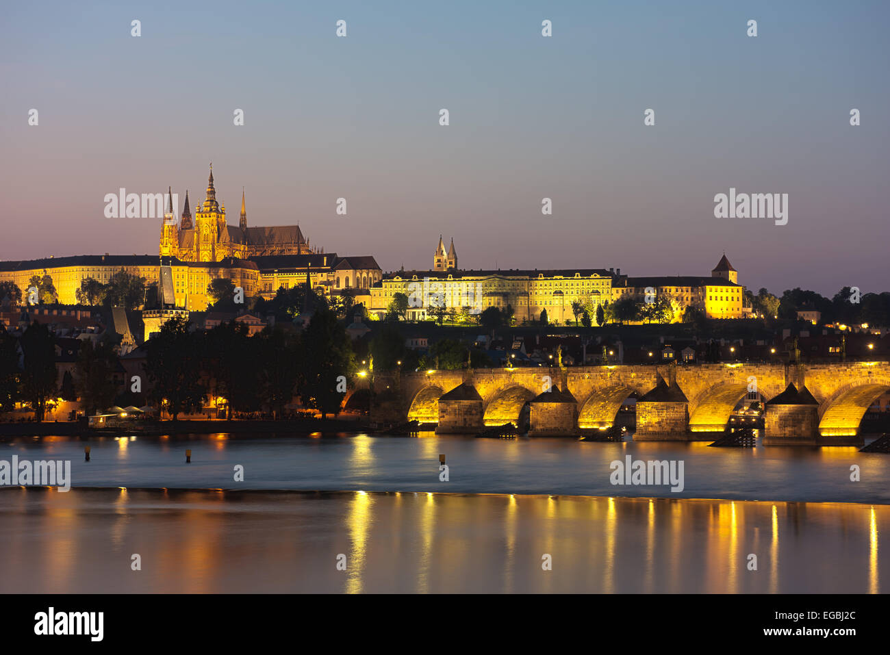 Prague at dusk showing Charles Bridge crossing the Vitava River with Prague Castle and St Vitus Cathedral in beyond. Stock Photo