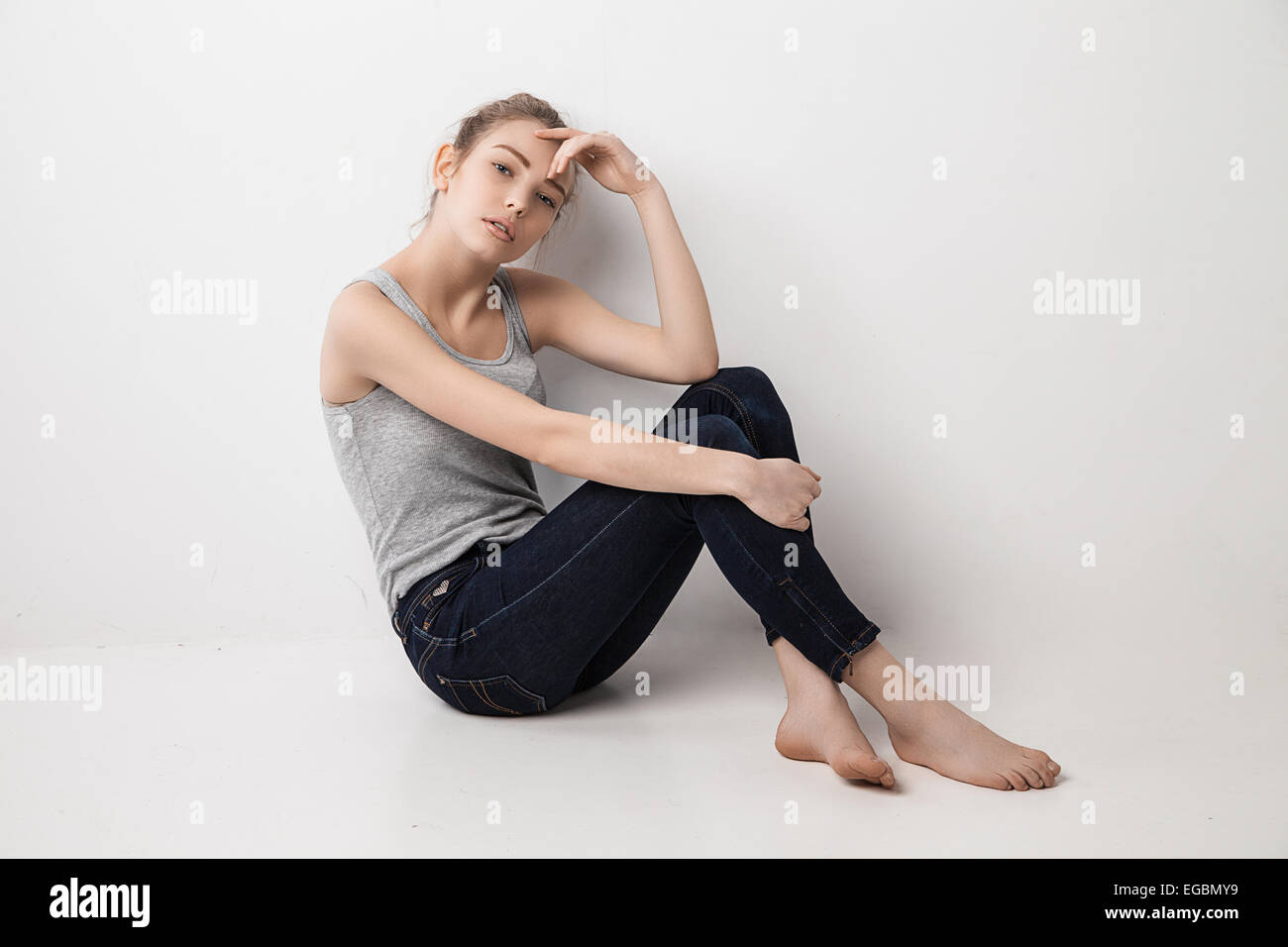 Beautiful melancholic girl sitting on the floor Stock Photo - Alamy