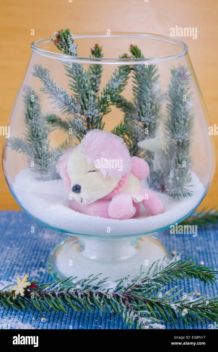 A toy dog sleeping on snow in a glass bowl Stock Photo