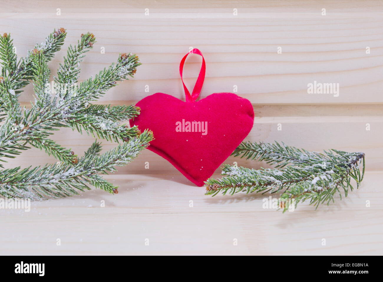 Heart and fir branches covered with snow on a wooden surface Stock Photo