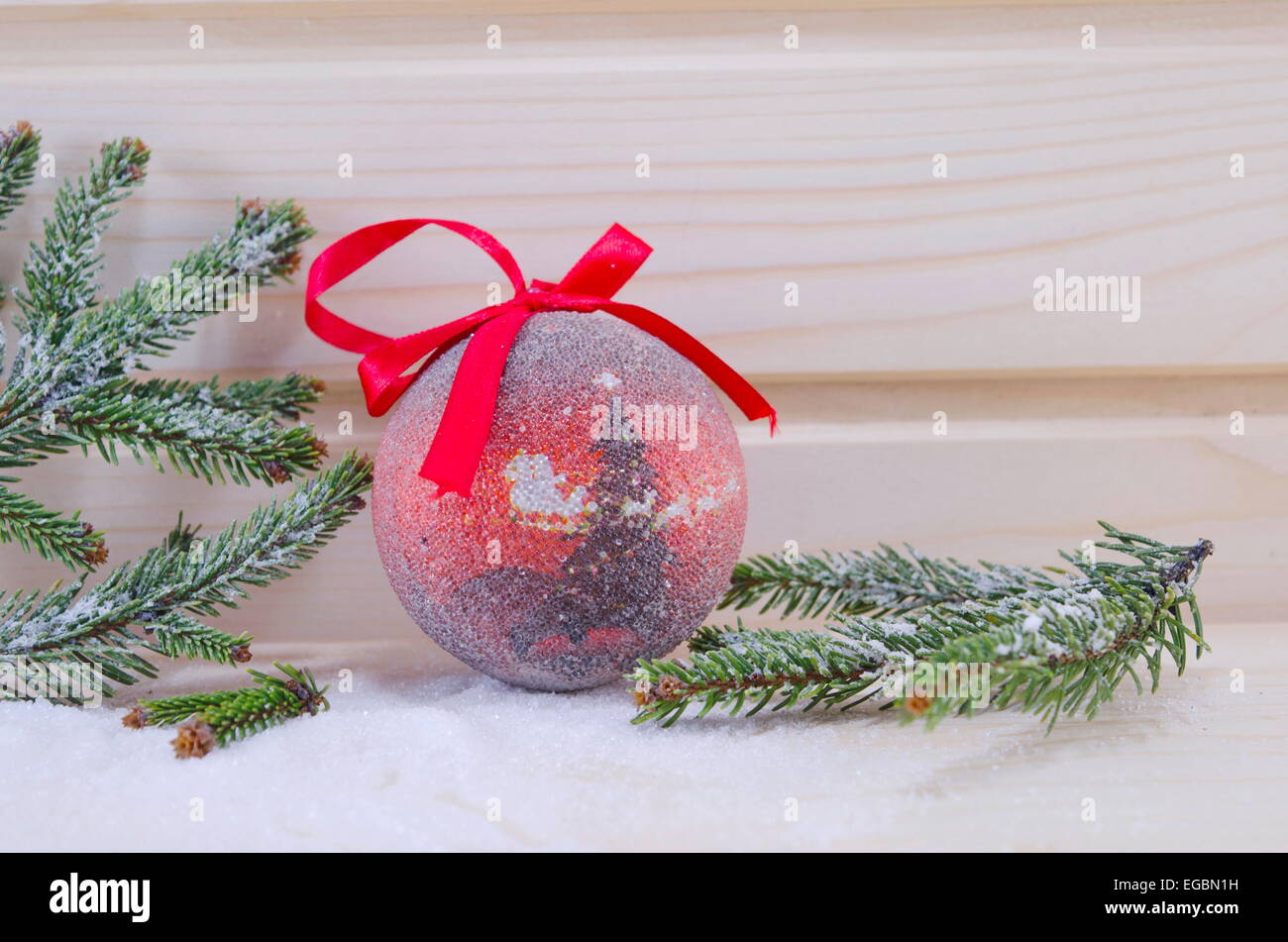 Red vintage Christmas ornament with a fir tree embedded on a wooden background Stock Photo