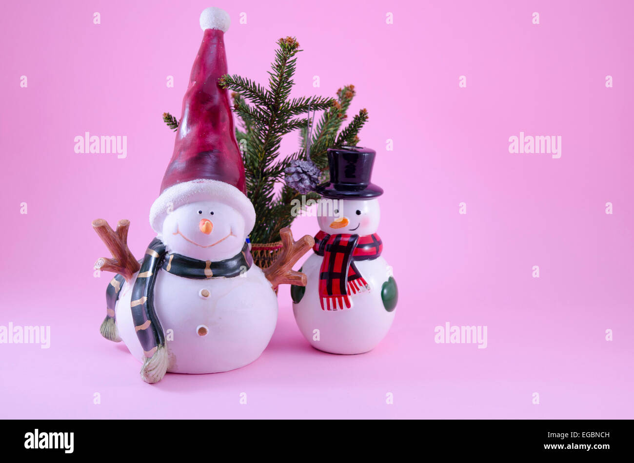 Two snowmen and a fir tree on pink Stock Photo