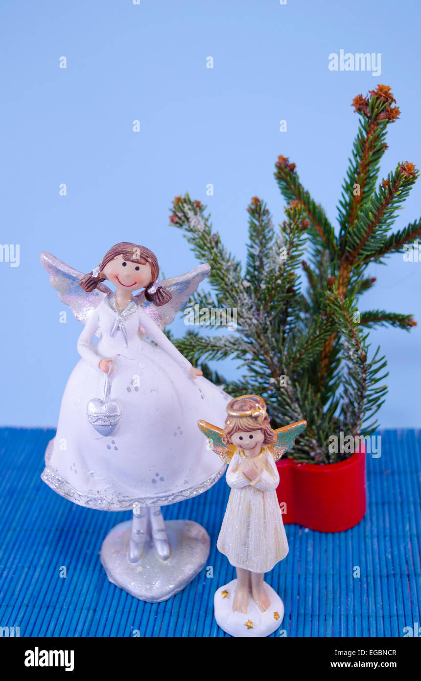 Two angel figurines and a fir tree on blue Stock Photo