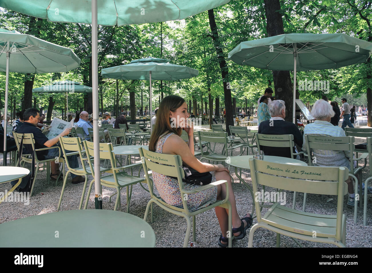 Young woman sitting alone at outdoor cafe in Luxembourg gardens, Paris, France Stock Photo