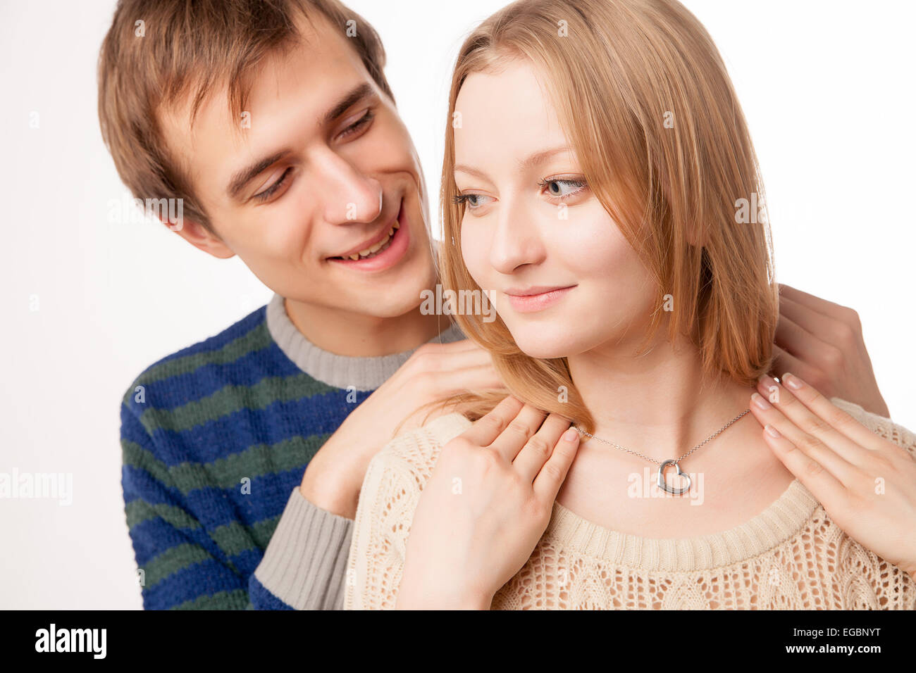 Man attaching necklace to girl's neck. man standing behind woman Stock