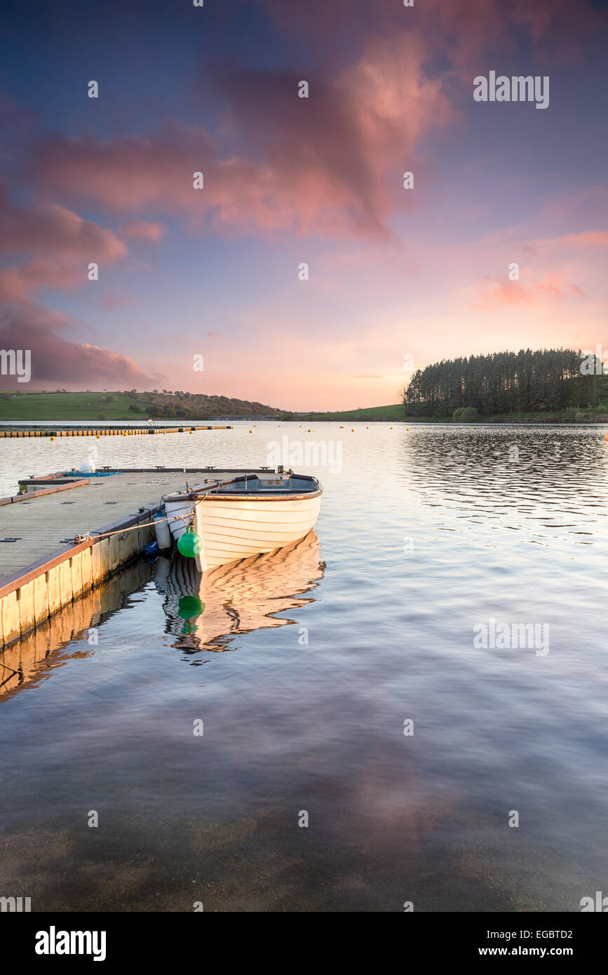 Wooden rowing boat moored to a jetty on Siblyback lake in Cornwall ...