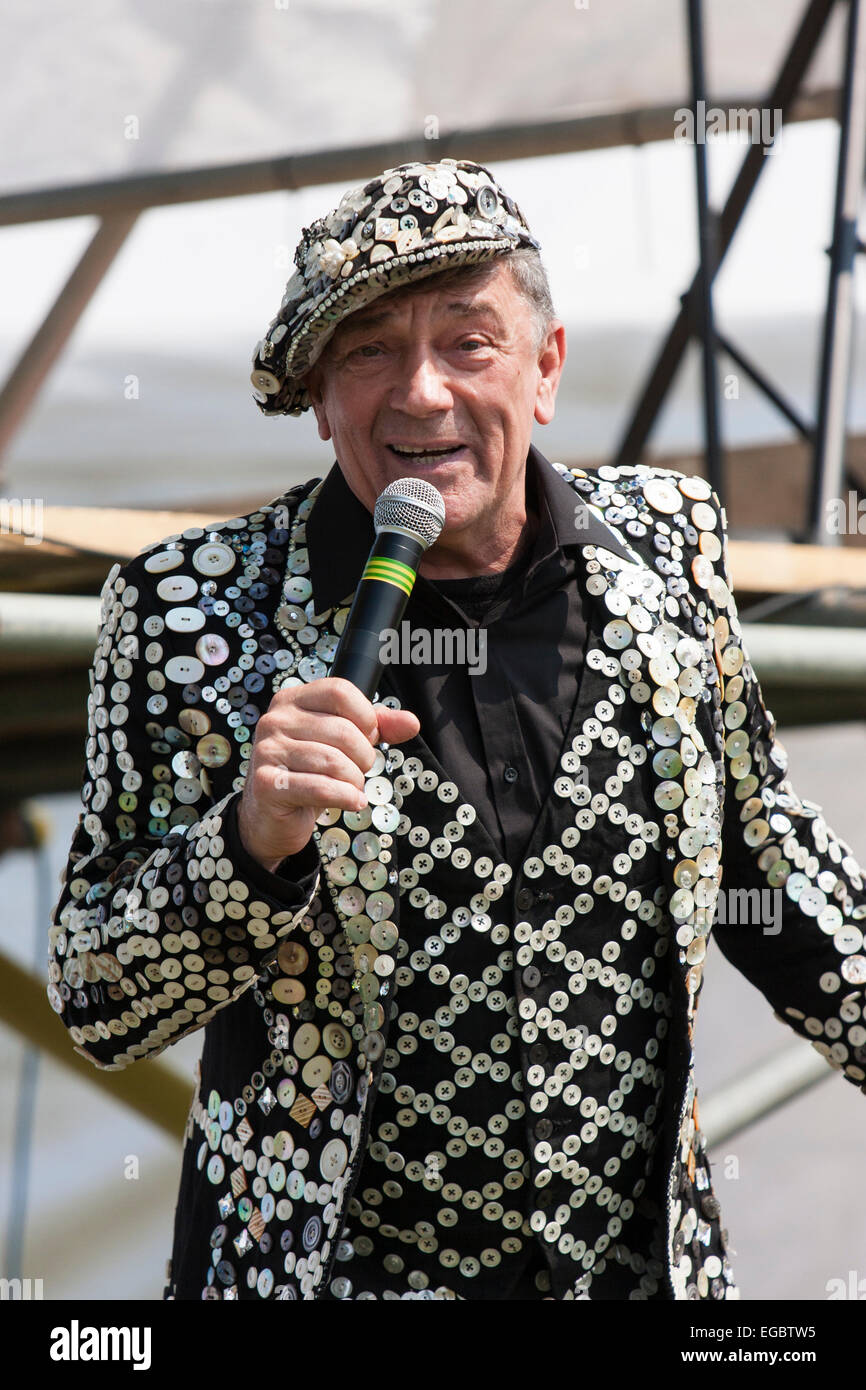 Mickie Driver, dressed in a pearly King waistcoat, jacket and hat, singing at an outdoor 1940s nostalgic event with hand held microphone. Stock Photo