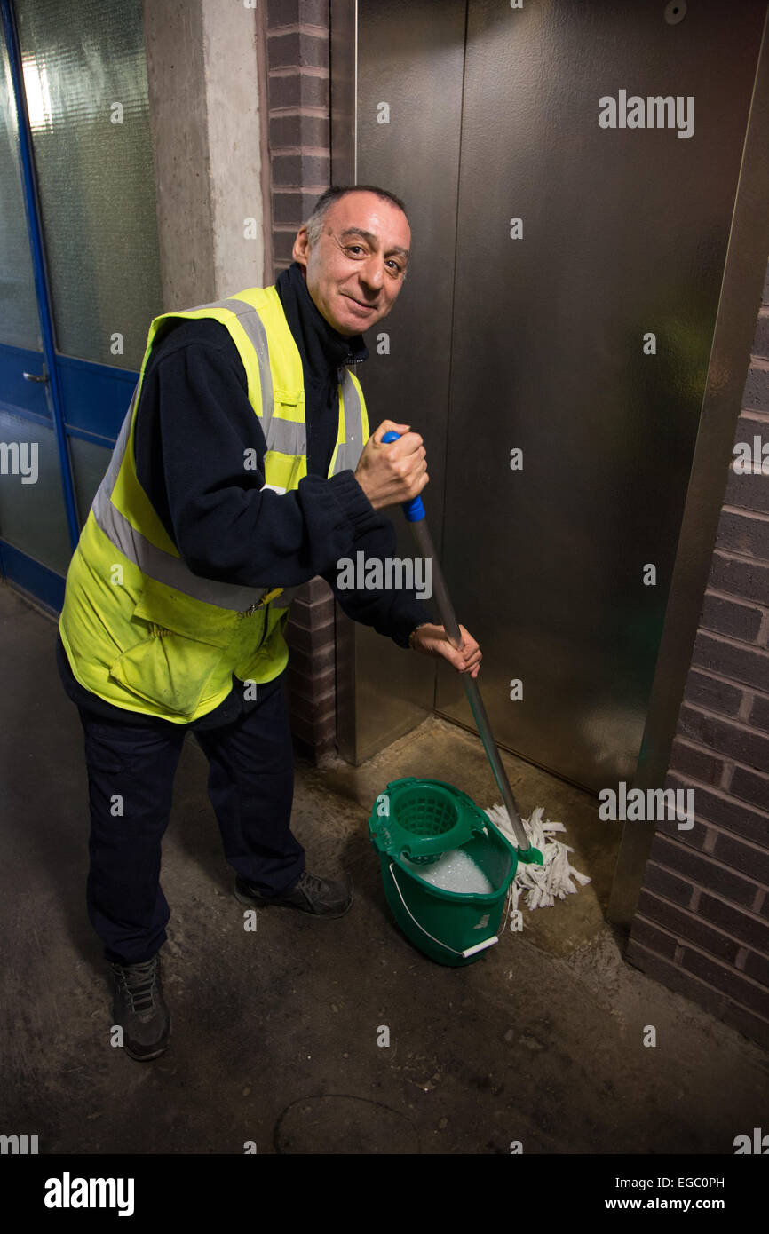 Man mopping the floor of a lift or elevator in a block of London flats Stock Photo