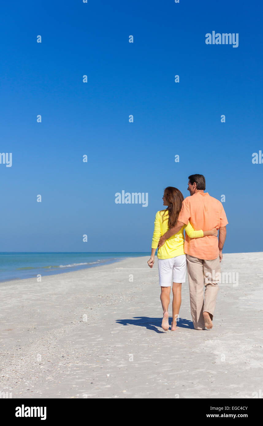 Rear view of man and woman romantic couple walking on a deserted ...