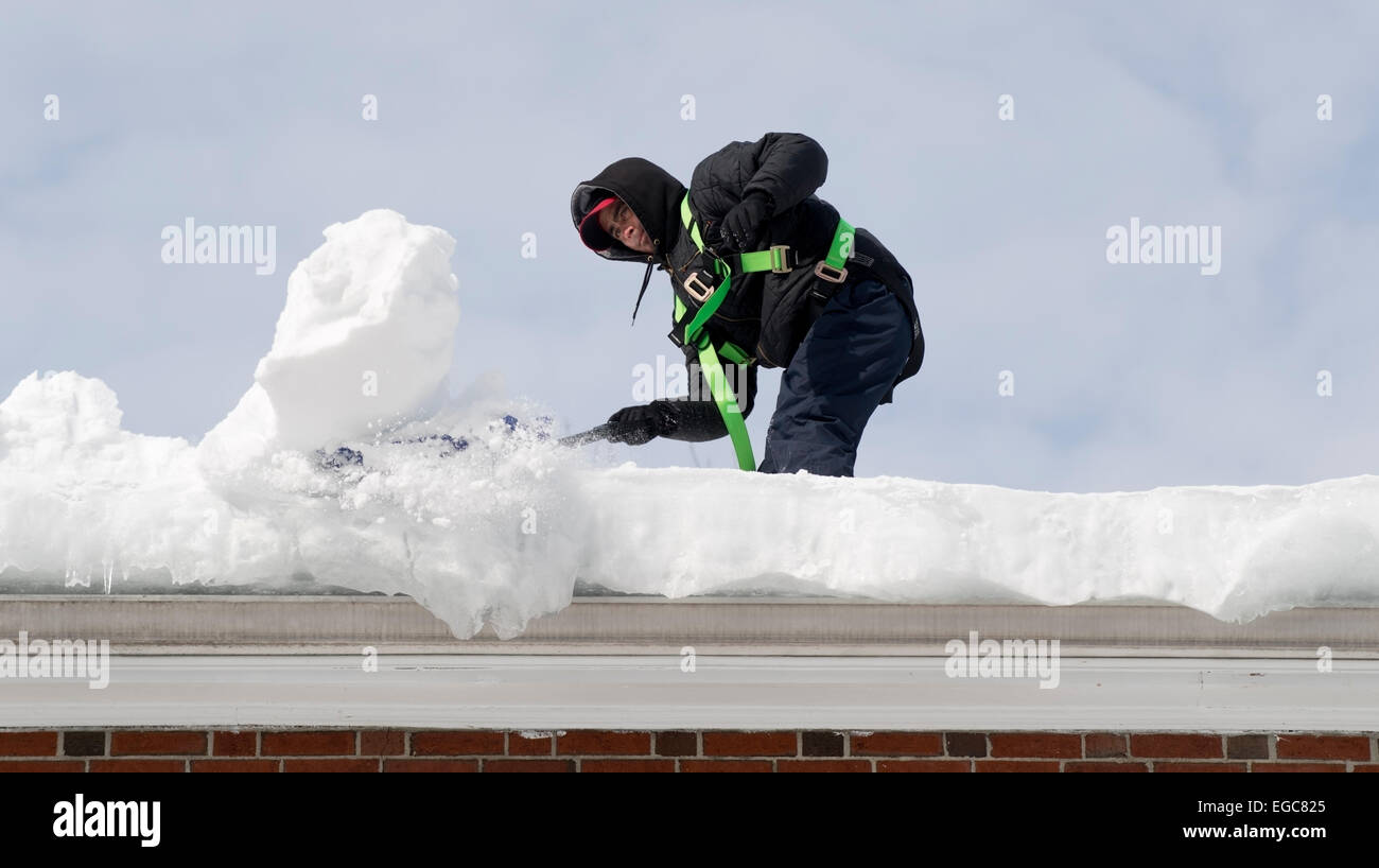 Lexington, MA, USA, 21 Feb, 2015. A workman cleaning snow from the roof of a three story apartment building in Lexington, MA, before another snow and ice storm hits Eastern Massachusetts. Credit:  Chuck Nacke/Alamy Live News Stock Photo
