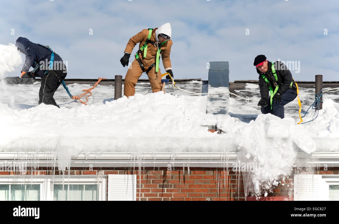 Lexington, MA, USA, 21 Feb, 2015. Workmen cleaning snow from the roof of a three story apartment building in Lexington, MA, before another snow and ice storm hits Eastern Massachusetts. Credit:  Chuck Nacke/Alamy Live News Stock Photo