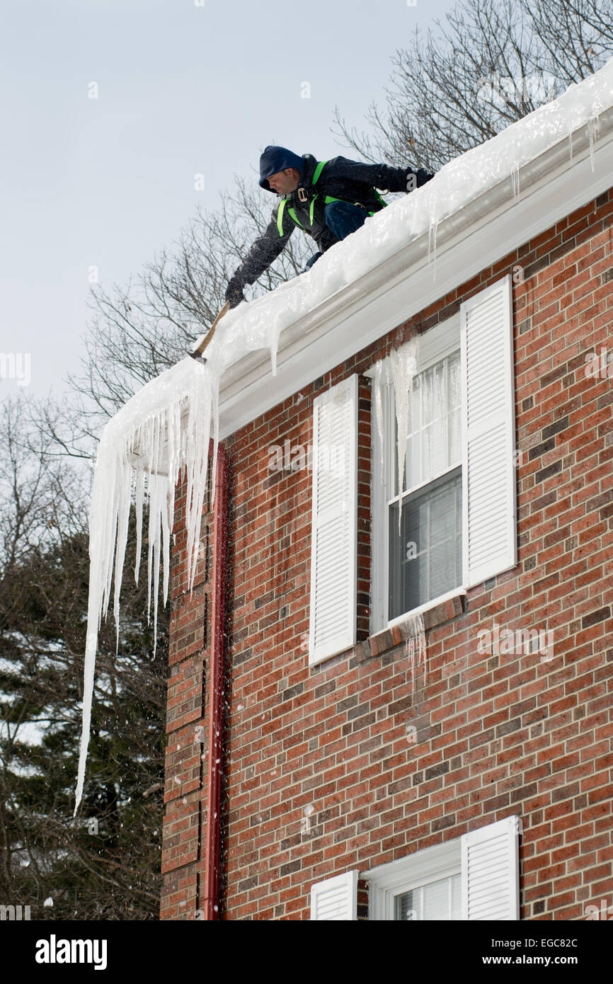Lexington, MA, USA, 21 Feb, 2015. Contractor chipping hanging ice hanging at the roof of a three story apartment building in Lexington, MA, before another snow and ice storm hits Eastern Massachusetts. Credit:  Chuck Nacke/Alamy Live News Stock Photo