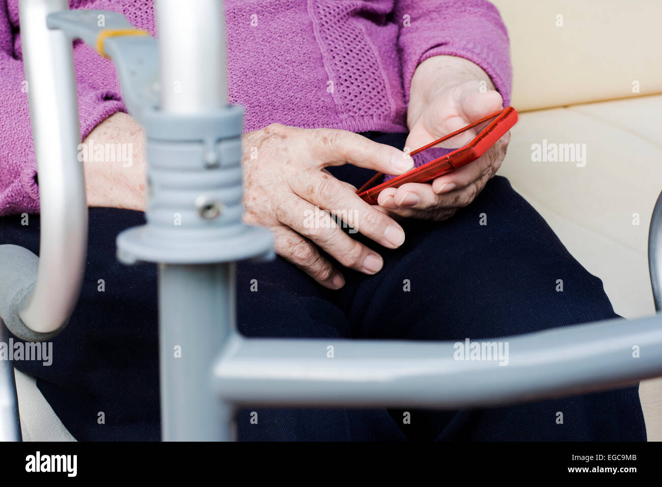 Elder woman with a smartphone and orthopedic walker texting messages Stock Photo
