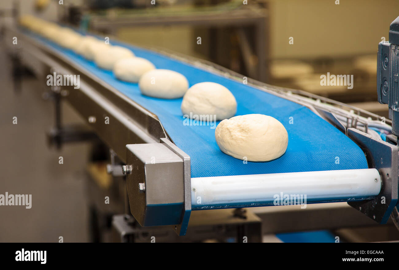 Bread bakery food factory. The pieces of raw dough move along a conveyor. Stock Photo