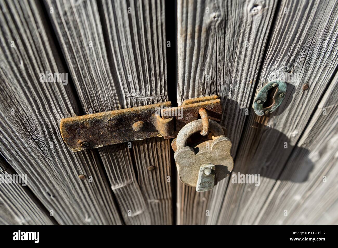 Old and rusty padlock secures an old, weathered wooden door Stock Photo ...