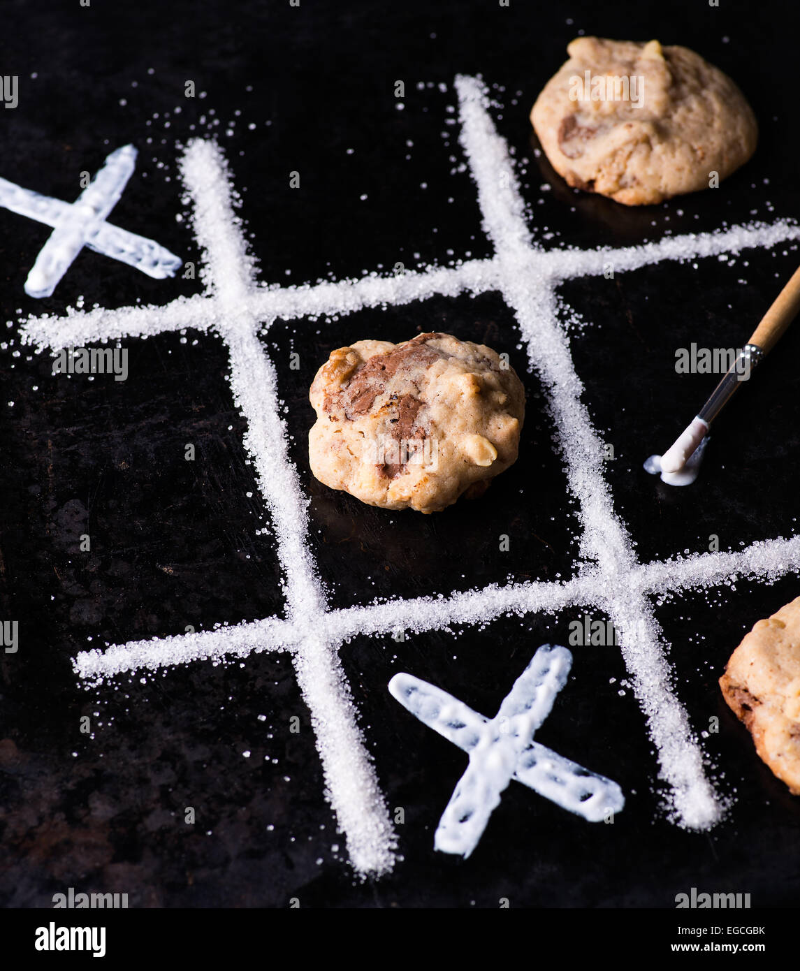 Chocolate chip cookies on noughts and crosses sugar grid, dark background, creative image, selective focus Stock Photo