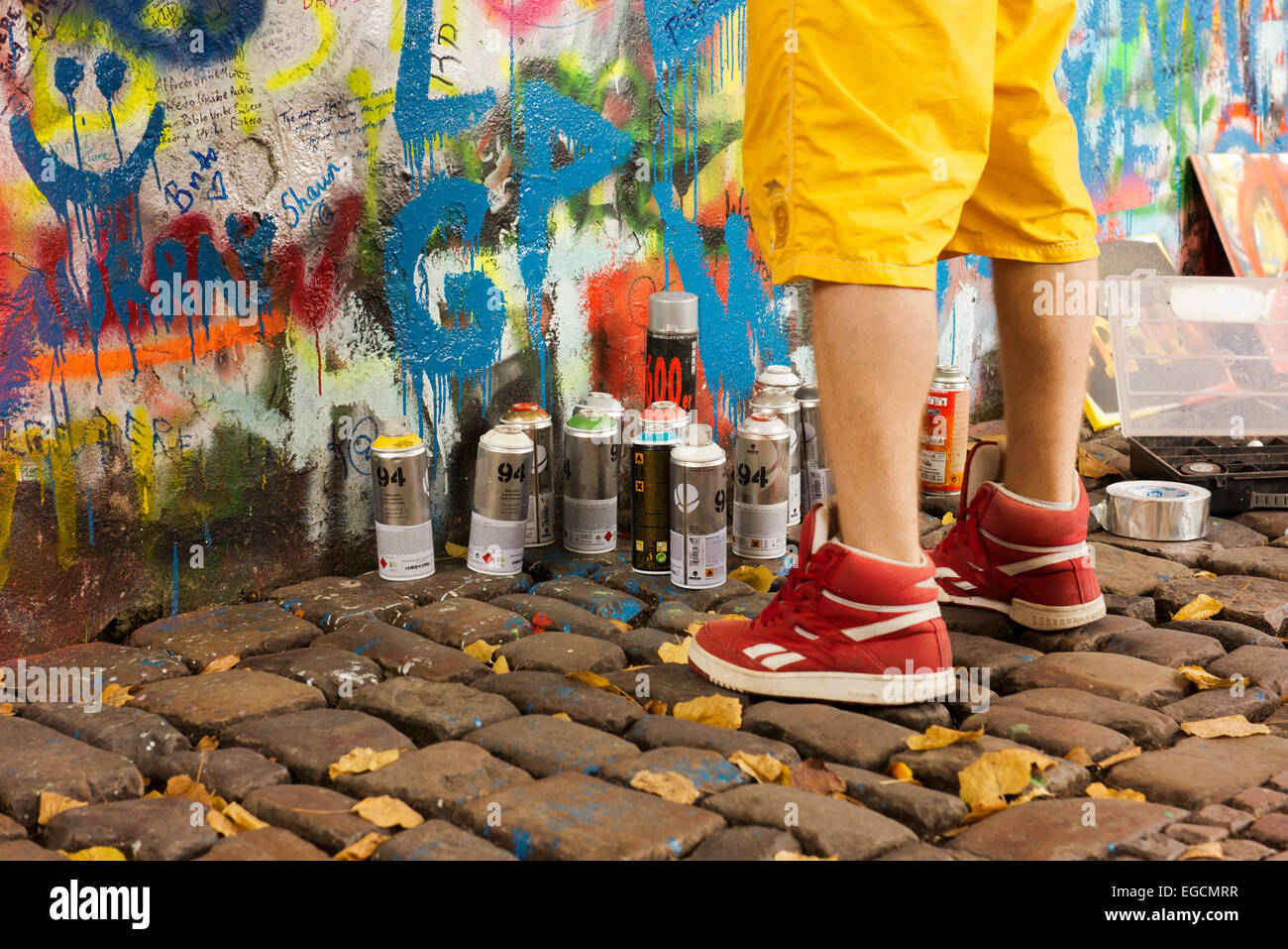 Feet and paint cans of a spray-paint artist working at The Lennon Wall in Prague. Stock Photo