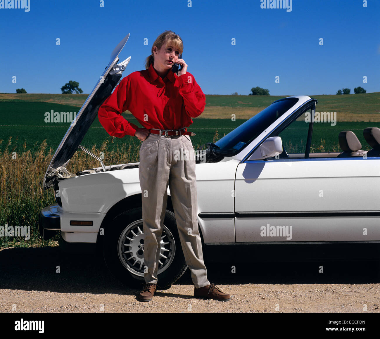 1990s WOMAN WITH CAR TROUBLE SPEAKING REQUESTING ASSISTANCE ON OLDER CELLULAR MOBILE PHONE Stock Photo