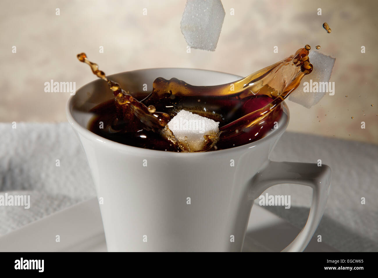 Sugar cubes falling into a cup of coffee, splashing coffee Stock Photo