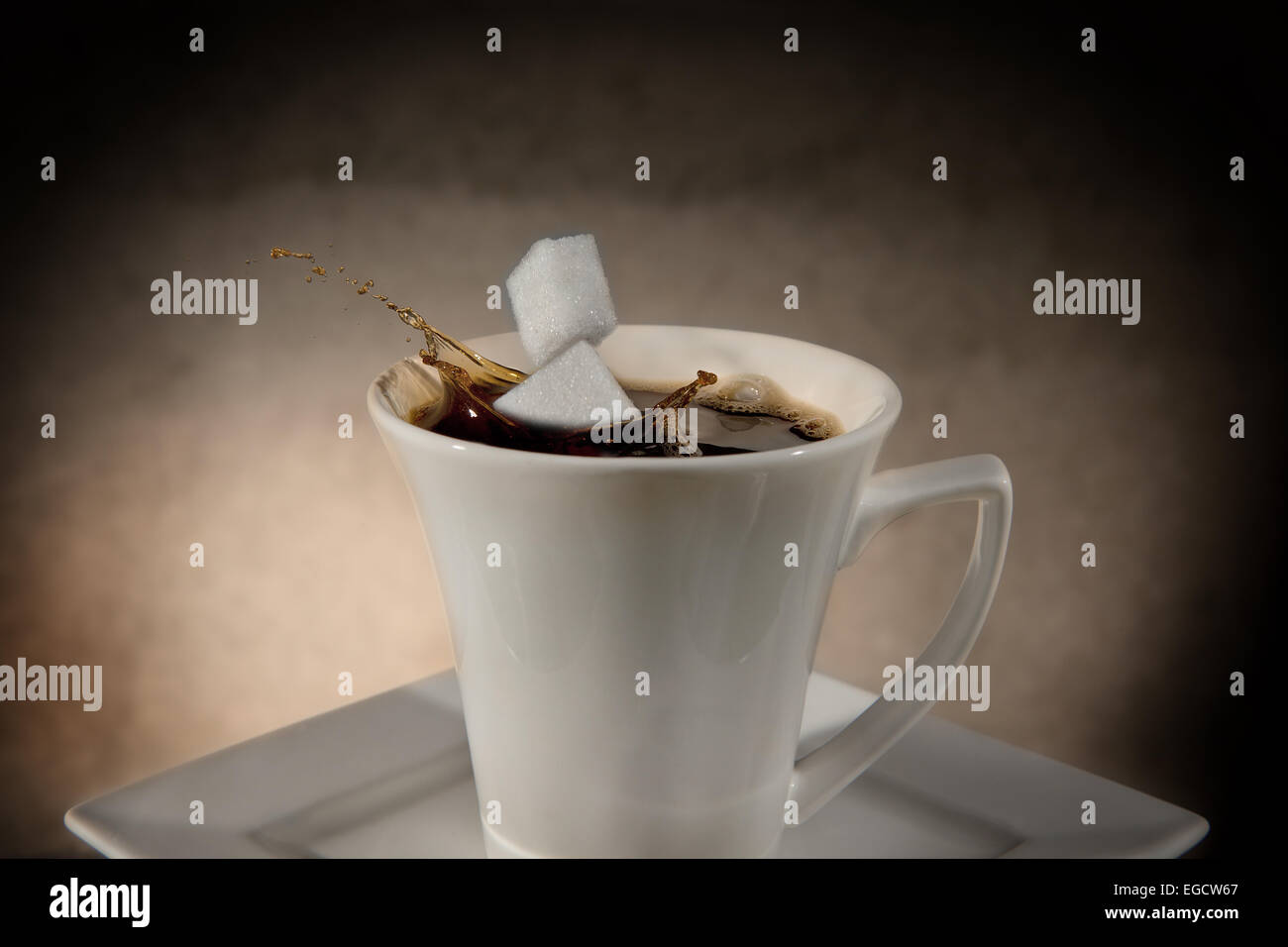 Two sugar cubes falling into a cup of coffee, splashing coffee Stock Photo