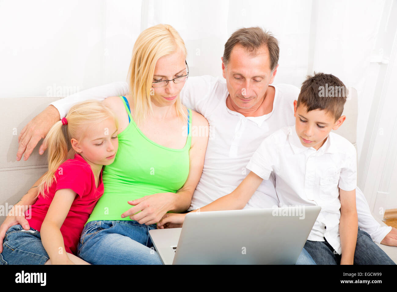 Happy family sitting together on the couch Stock Photo - Alamy