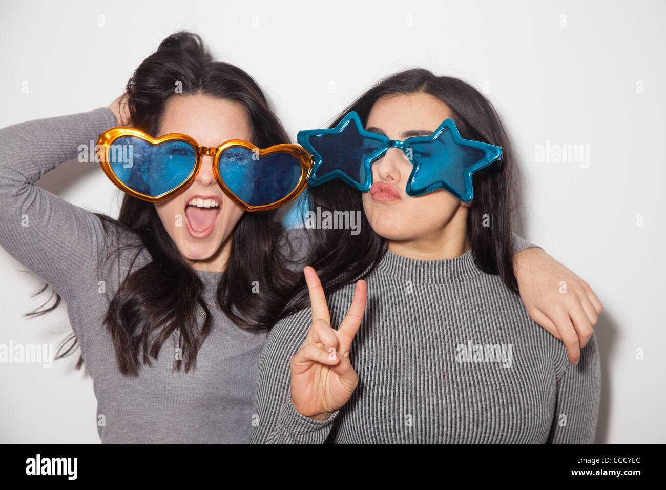 Two sisters having fun together wearing comedy oversize glasses. Stock Photo