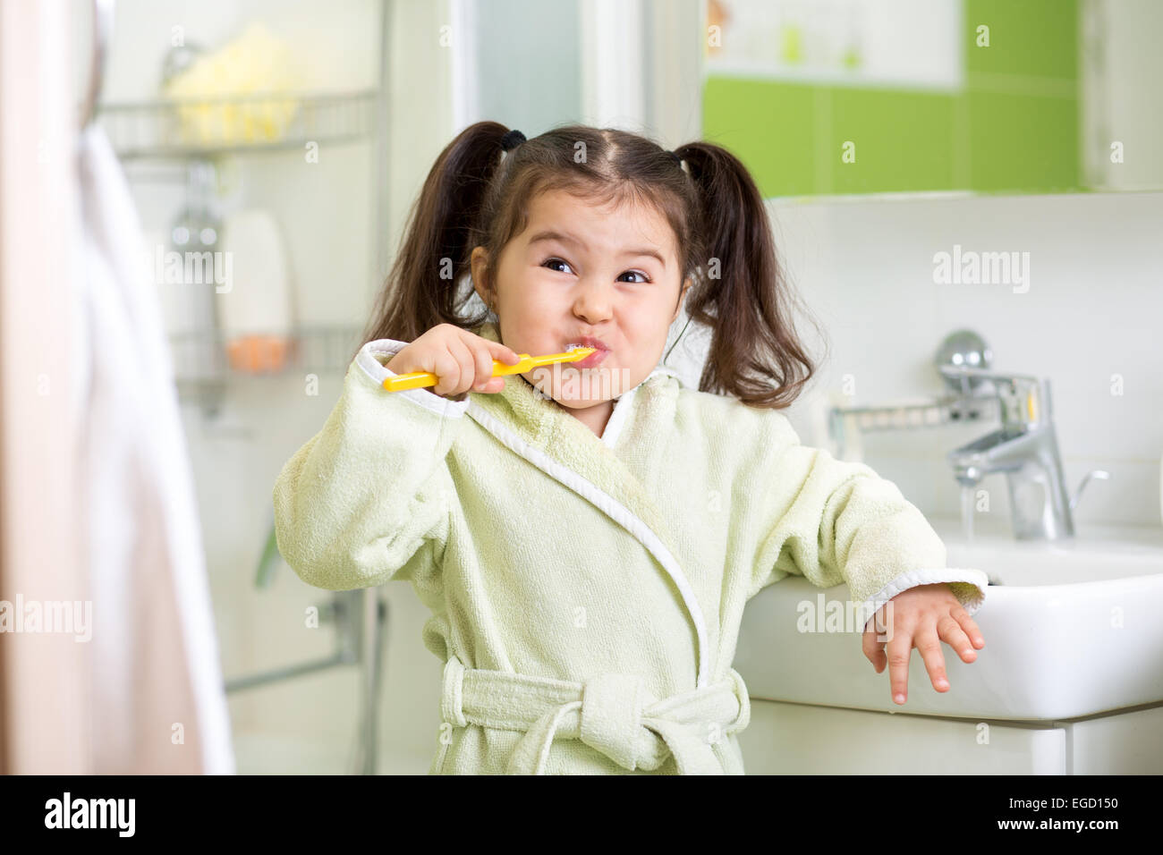 Smiling little girl brushing teeth in bathroom Stock Photo