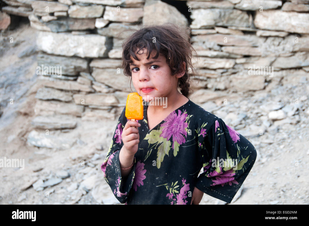 Kabul, Afghanistan, poor neighbourhood. Young girl looking defiant and licking a lollipop Stock Photo