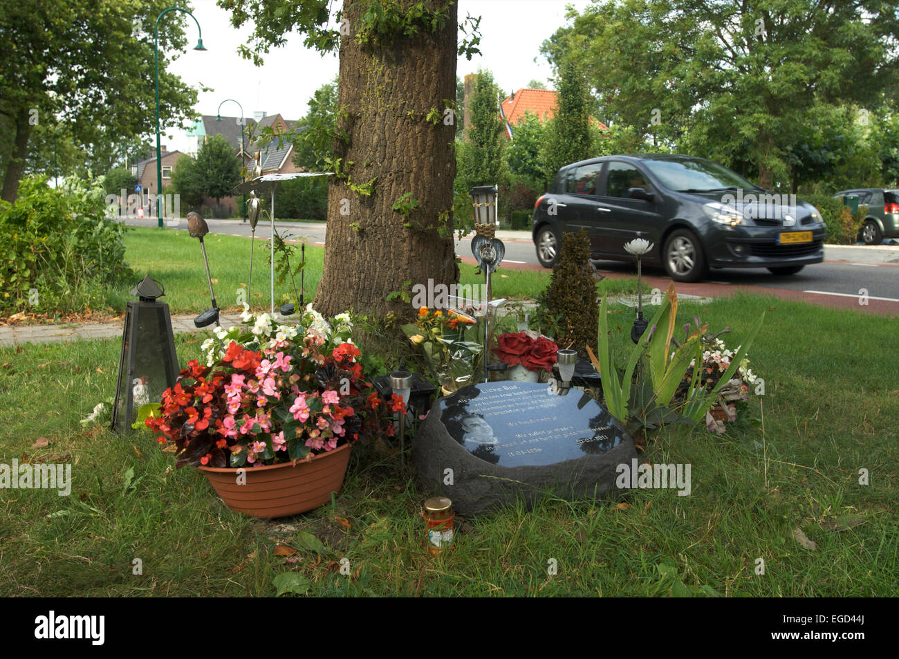 A monument next to the road in memory of a person who died here in a car crash when he hit the tree, The Netherlands Stock Photo