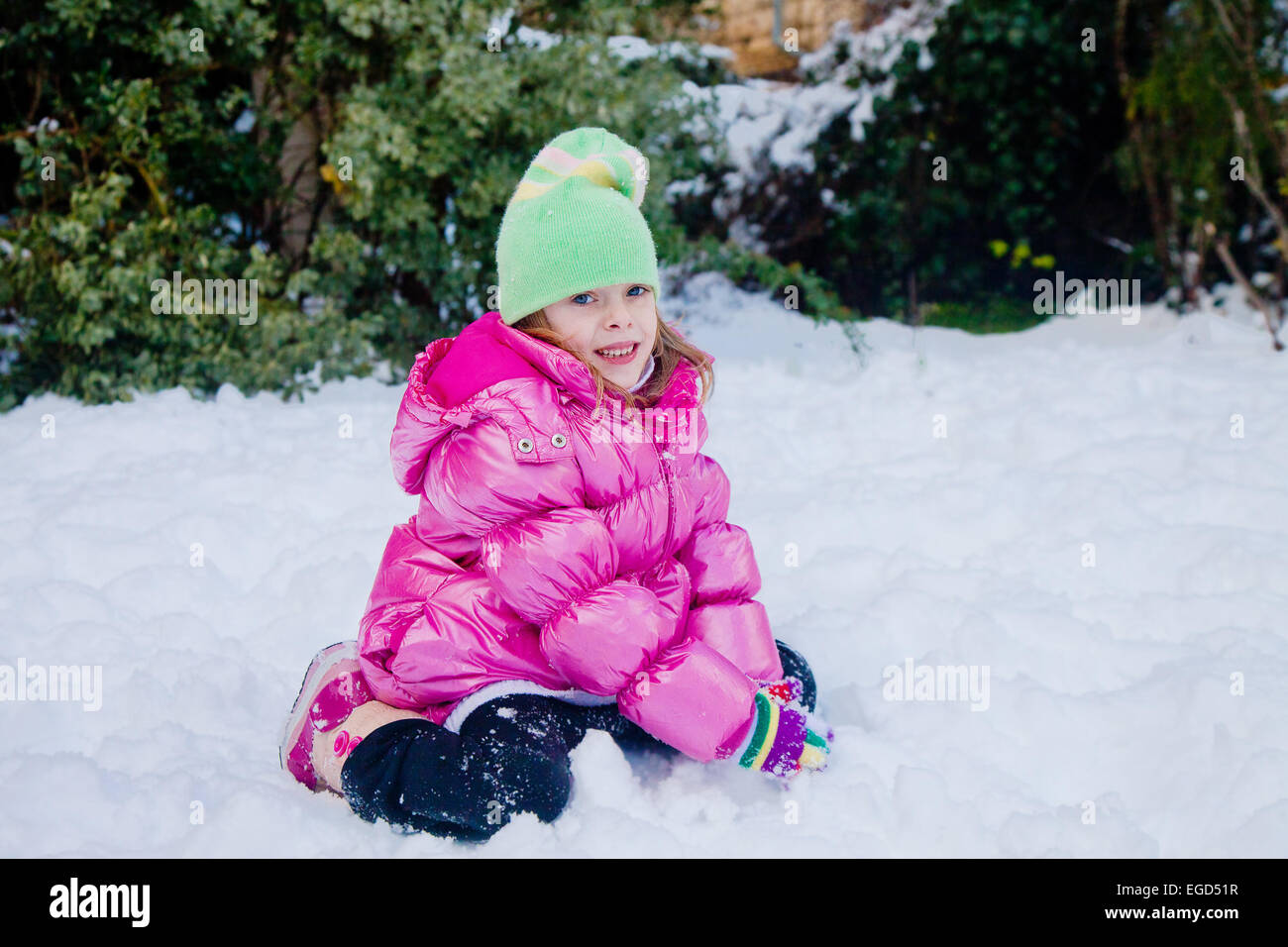 POrtrait of a cute little girl playing in the snow in her backyard in ...