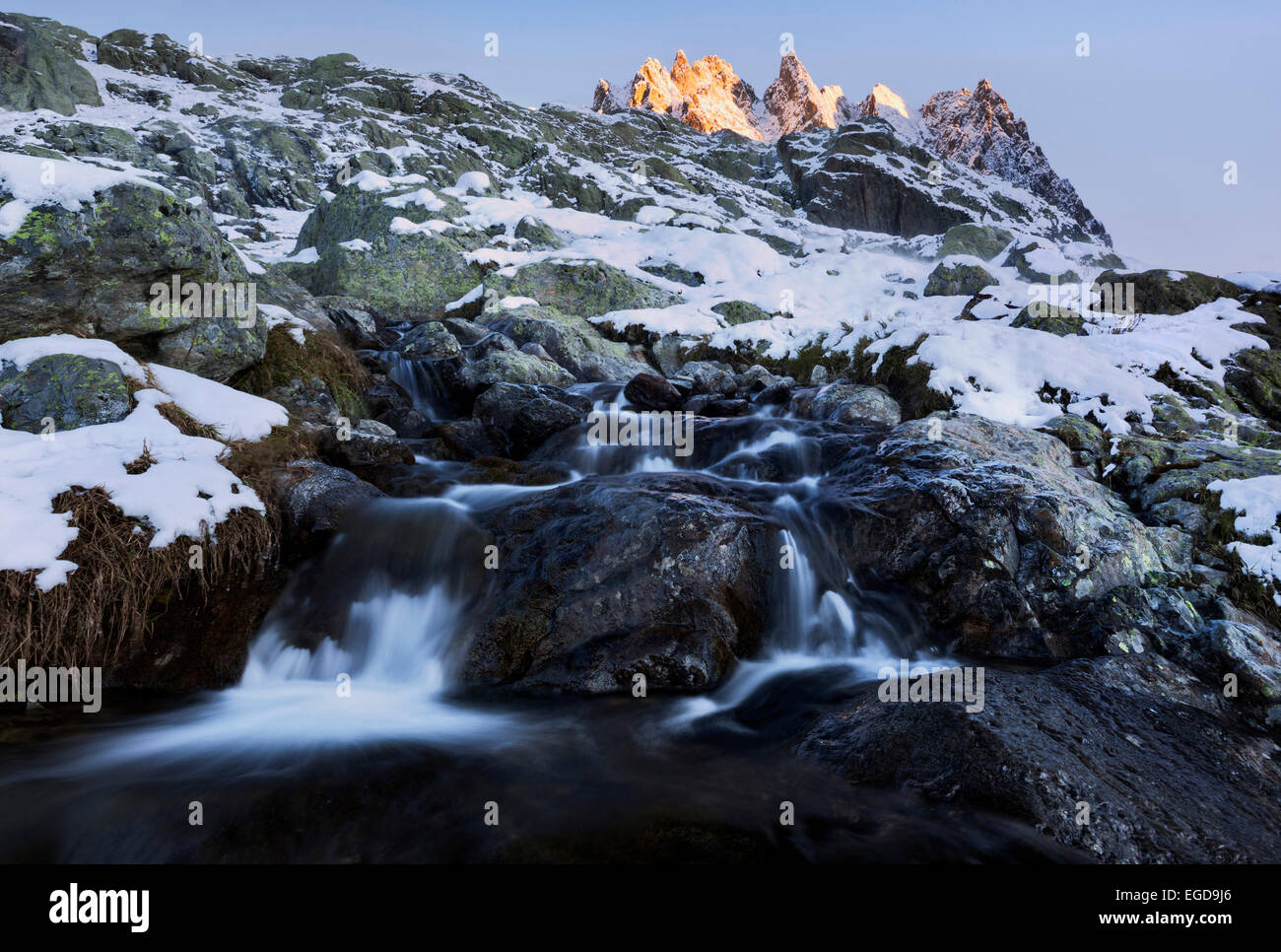 Sunrise over the snowy French Alps with mountain stream and the peak of Aiguille de l'Encrenaz in Autumn, Savoy, France Stock Photo