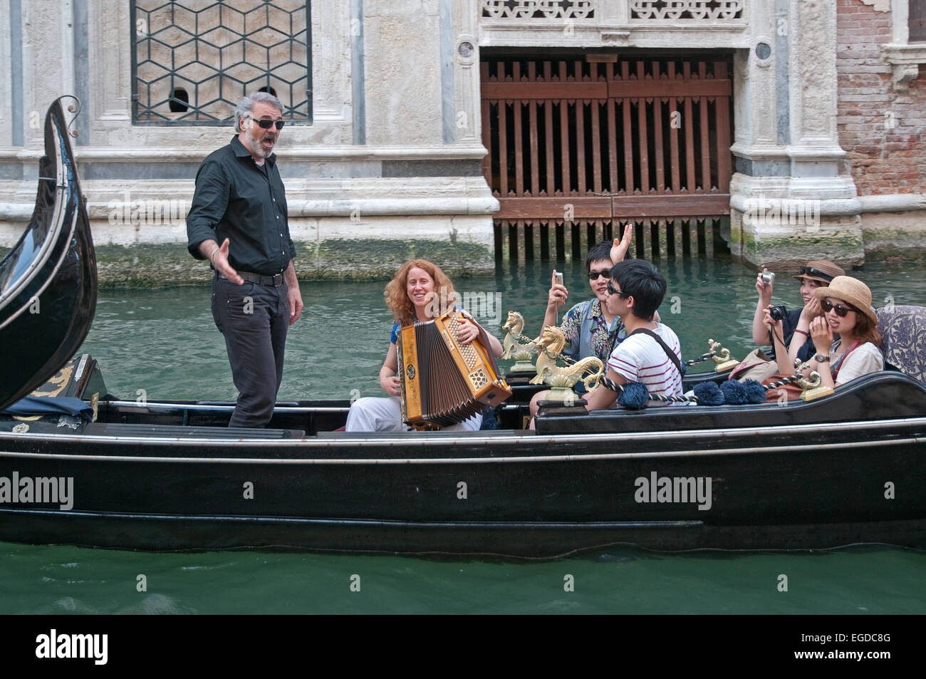 Male opera singer entertains family on godola going on Rio de Palazzo de Canonica Venice Italy near Bridge of Sighs Stock Photo