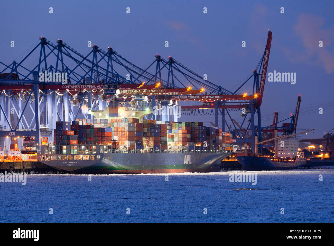 Container ship in front of a container bridge in winter, Altenwerder, Hamburg, Germany Stock Photo