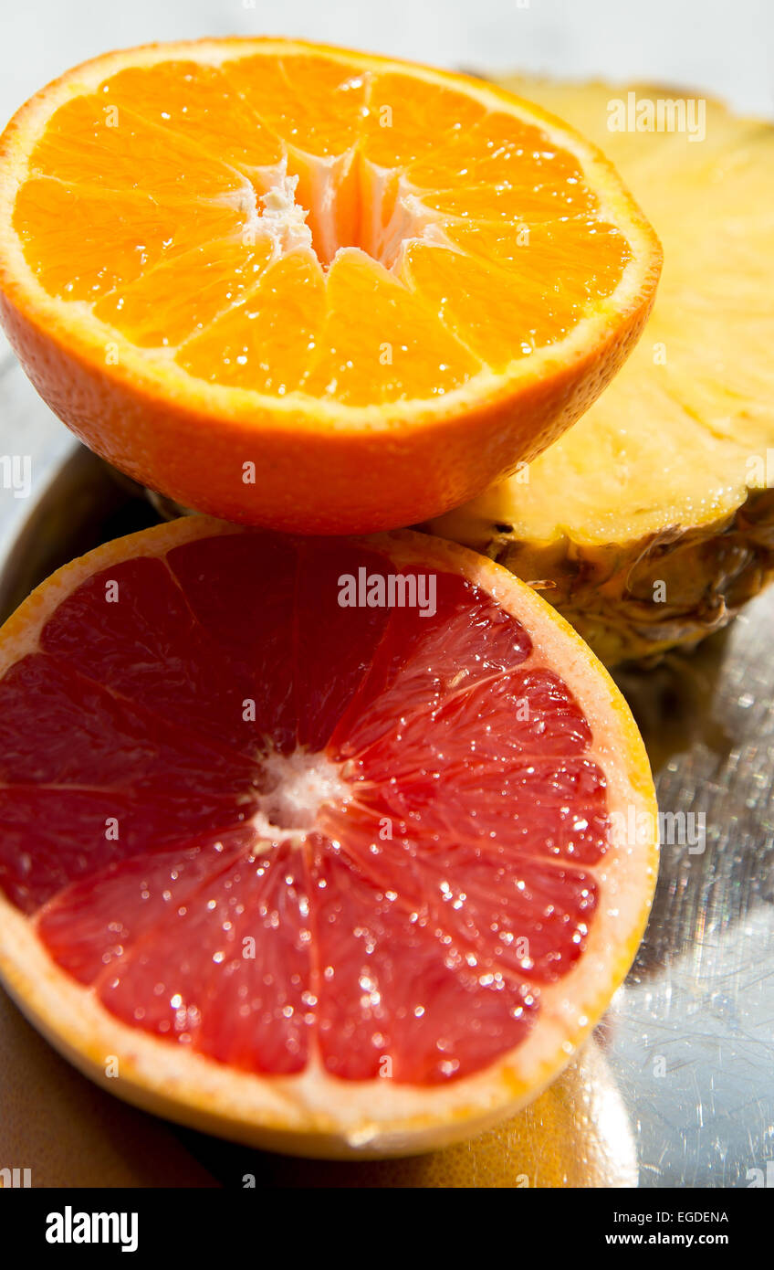 Grapefruit, orange and pineapple sitting on display ready to eat in the sunlight. Stock Photo